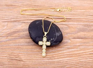 Gold cross pendant necklace featuring sparkling cubic zirconia stones for detail fashion view.