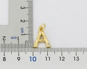 Detail view of a hammered bamboo letter A initial pendant in 18k gold plated finish with stone.