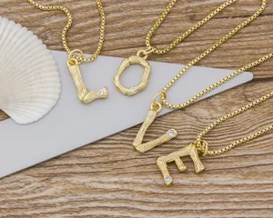 Detail shot of gold-plated bamboo initial letter pendants on chain, minimalist chic style.