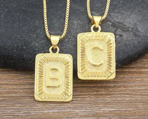 Gold-plated hip hop initial letter B and C pendant necklace close-up, textured metal jewelry detail.