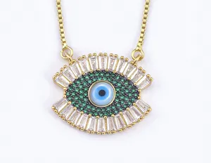 Closeup detail of gold plated evil eye pendant necklace with green and white cubic zirconia stones.