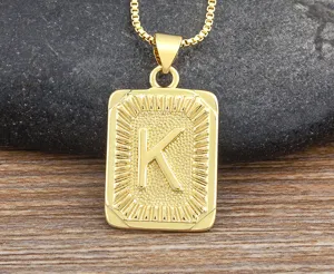 Closeup of gold letter K pendant necklace on rustic wooden and stone background, detailed craft.