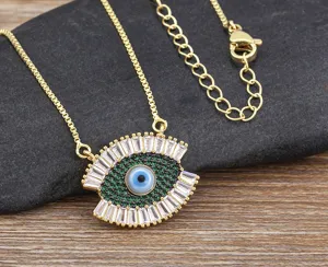 Evil eye necklace pendant detail view, gold tone metal with green and white crystal stones.