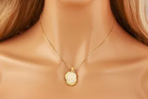 Close-up of gold initial letter pendant necklace, irregular geometric design detail.