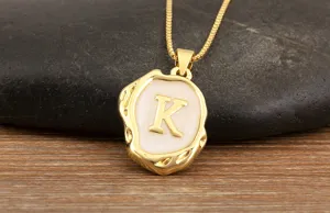 Gold plated initial necklace detail showing the white enamel irregular pendant with letter K.