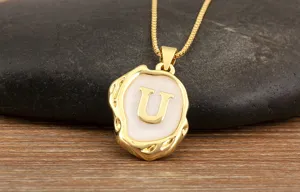 Gold-plated initial letter U pendant necklace with irregular enamel design, detailed shot.