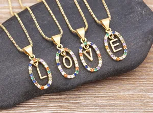 Detailed close-up of colorful cubic zirconia letter pendant necklaces on dark stone background.