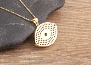 Gold evil eye pendant necklace detail close-up, vintage style chic clavicle chain jewelry.