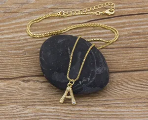 Gold letter A pendant necklace detail close-up shot, minimalist dainty jewelry on display stone.
