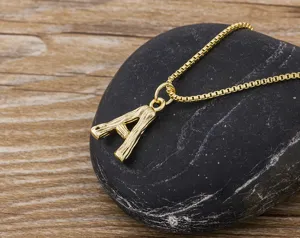 Detailed close-up of gold letter A pendant necklace featuring bamboo texture on black stone.