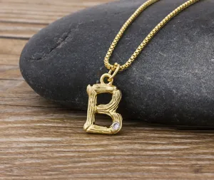 Close-up detail of a minimalist gold-plated letter B pendant necklace with bamboo texture.