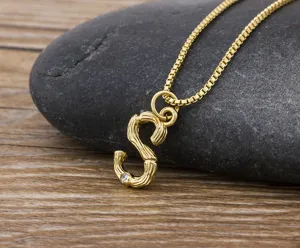 Close up of gold initial S bamboo letter pendant necklace with sparkling crystal detail.