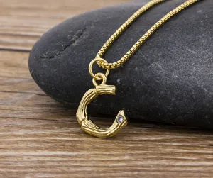 Detailed close-up of a gold-plated bamboo letter C pendant necklace featuring a sparkling stone.