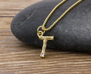 Close-up of a gold-plated letter T pendant necklace with a sparkling crystal on stone.