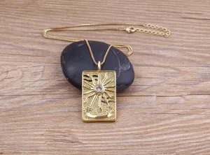 Gold tarot card pendant necklace with sparkly rhinestone sun design on wooden background detail