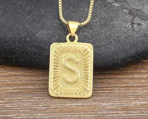 Detail shot of hip hop gold plated letter S pendant necklace on textured background.