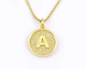Detail shot of golden round letter pendant necklace featuring sparkling stone, fine box chain.