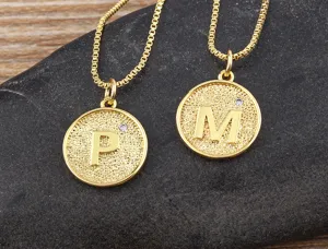 Closeup of gold plated alphabet letter pendants with sparkling zirconia details on stone.