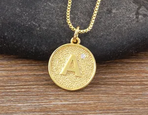 Close-up detail of the gold-plated round letter pendant necklace with sparkling zirconia.