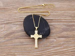 Detailed view of gold plated cross pendant necklace with sparkling zirconia stones on display.