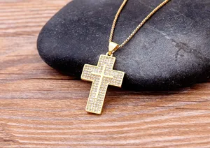 Close-up detail shot of a sparkling cubic zirconia paved cross pendant necklace on dark stone.