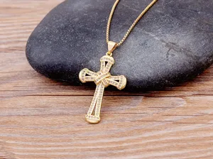 Close-up detail of a gold-plated cross pendant necklace featuring sparkling micro-set zirconia.
