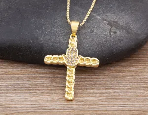Close-up detail of a gold-plated cross pendant necklace with sparkling cubic zirconia stones.