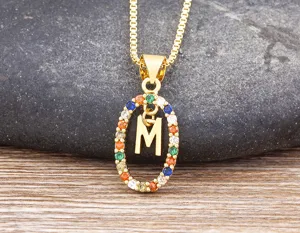 Close up of gold plated initial M letter necklace decorated with colorful cubic zirconia stones.