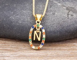 Close-up of a stylish gold-plated colorful zircon letter N pendant necklace on a stone.