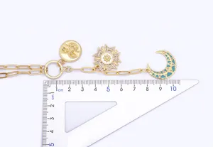 Dettaglio della collana dorata con ciondolo croce in zirconi e luna smaltata blu.