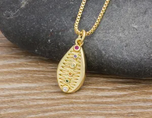 Detail close-up of a gold-plated teardrop pendant necklace with colorful cubic zirconia stones.