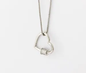 Gros plan sur le pendentif mousqueton en cœur avec cylindre pavé de strass brillants.