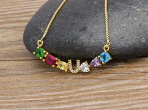 Close-up of colorful cubic zirconia letter U pendant necklace on stone background, exquisite detail.