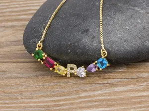 Gold-plated colorful cubic zirconia pendant and letter P detail closeup view on pebble