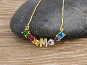 Detailed closeup of gold plated letter M necklace featuring colorful cubic zirconia stones.