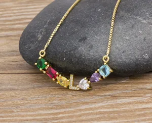 Gold-plated brass necklace detail with multi-color cubic zirconia and letter L pendant charm.