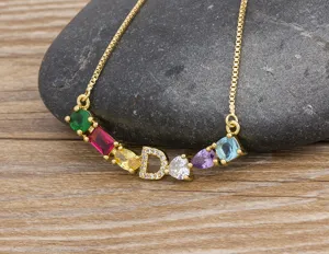 Detailed view of gold plated necklace with colorful zirconia and letter D pendant.