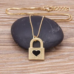 Collier cadenas cœur plaqué or avec détail émail noir sur fond en bois de présentation.
