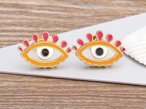 Detailed close-up of trendy enamel evil eye stud earrings in vibrant colors with gold trim.