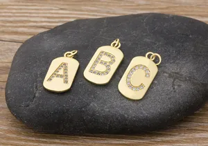 Close-up detail shot of gold-plated initial letter pendants with sparkling zirconia stones.
