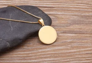 Close-up detail of the elegant minimalist gold round blank pendant necklace on stone prop.