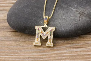 Close-up of gold-plated letter M pendant necklace with colorful cubic zirconia stones.