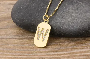 Gold initial letter W pendant necklace detail close-up showcasing micro-pave cubic zirconia on a stone.