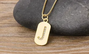 Close up of a gold letter J pendant necklace with sparkling cubic zirconia on wood background.