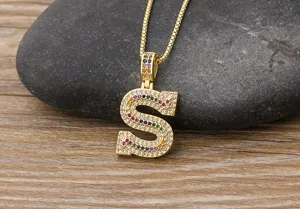 Close-up detail of the colorful paved cubic zirconia letter S pendant necklace on stone.