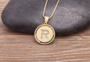 Gold initial letter R pendant necklace with colorful cubic zirconia pavé on wooden background