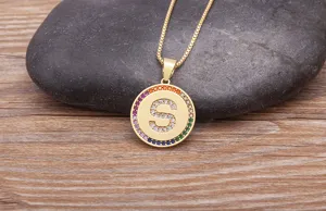 Gold letter S pendant necklace with colorful cubic zirconia, delicate jewelry detail shot.