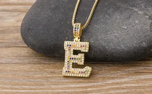 Close-up detail of a gold-tone letter E pendant necklace encrusted with colorful cubic zirconia.