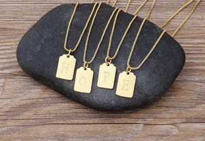 Collana con ciondolo quadrato con lettere dorate, dettaglio di bigiotteria elegante.
