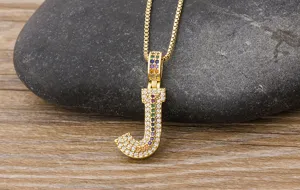 Close-up detail of a gold-plated letter J pendant necklace with colorful sparkling zircon stones.